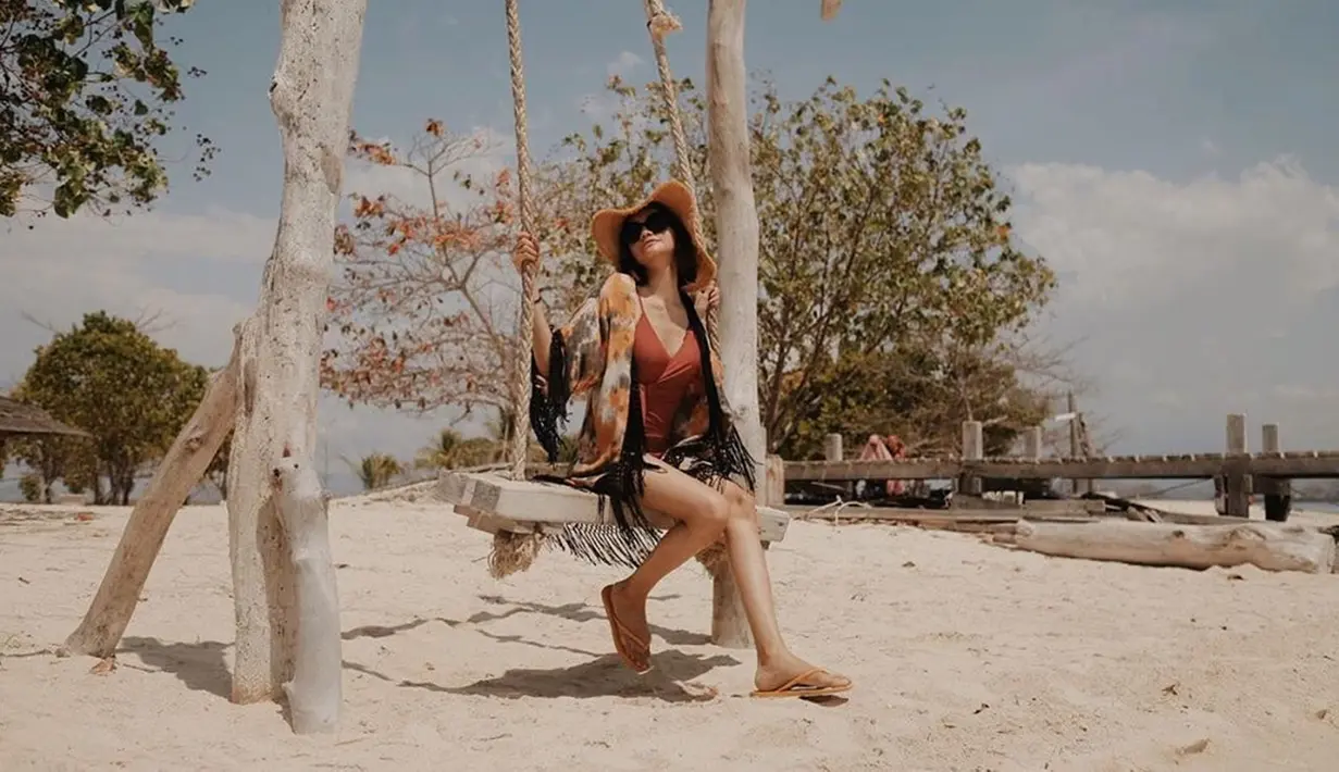 Saat bermain di pantai, Gesya tak lupa menikmati suasana dengan duduk di atas ayunan. Gayanya yang trendi dengan kaca mata dan topi, membuat perempuan berusia 25 tahun ini menyita perhatian. (Liputan6.com/IG/@gesyashandy)