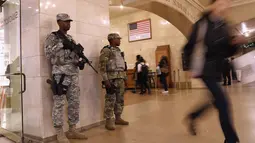 Pasukan Garda Nasional bersenjata laras panjang berjaga di terminal Grand Central, New York City, pasca teror bom pipa, Senin (11/12). Empat orang, termasuk pelaku dikabarkan mengalami luka-luka akibat teror bom tersebut. (JOHN MOORE / GETTY IMAGES / AFP)