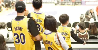 Sandra Dewi dan keluarganya sedang berada di Los Angeles. Ia membagikan beberapa potret ia dan suami, serta anak-anaknya menyaksikan langsung pertandingan basket NBA. [Foto: Instagram/sandradewi88]