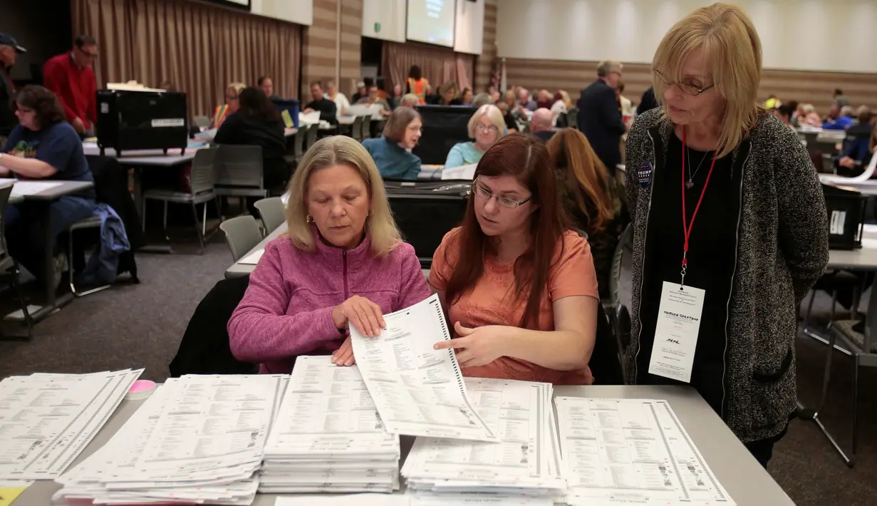 Petugas meneliti kembali surat suara pemilihan Presiden AS di Waterford Township, Michigan, Amerika Serikat (5/12). Menurut komisi pemilihan Wisconsin, batas waktu penghitungan ulang adalah 13 Desember. (Reuters/Rebecca Cook)