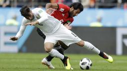 Gelandang Uruguay, Rodrigo Bentancur, berebut bola dengan striker Mesir, Marwan Mohsen, pada laga Piala Dunia di Stadion Ekaterinburg, Jumat (15/6/2018). Uruguay menang 1-0 atas Mesir. (AP/Natacha Pisarenko)