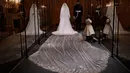 Gaun pernikahan Meghan Markle dan Pangeran Harry ditampilkan pada pameran A Royal Wedding di Kastil Windsor, London, 25 Oktober 2018. Gaun yang dikenakan Meghan, dipajang di kotak kaca besar di samping kostum pernikahan Pangeran Harry. (AP/Matt Dunham)