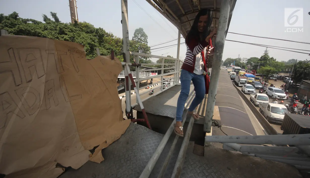 Pejalan kaki melewati lubang di atas JPO di Halte Bus Transjakarta di Jembatan Gantung, Cengkareng, Jakarta, Jumat (27/7). JPO yang rusak akibat tertabrak truk sejak setahun lalu hingga kini belum diperbaiki.  (Liputan6.com/Arya Manggala)