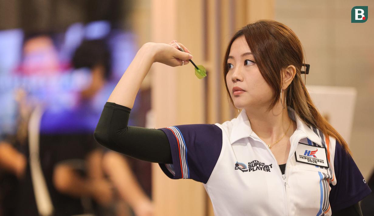 Dartslive Support Player asal Singapura Hedy Wong mencoba salah satu alat di acara peluncuran Darts Station di lantai F7 FX Sudirman, Senayan, Jakarta pada Sabtu (15/11/2025). (Bola.com/Abdul Aziz)