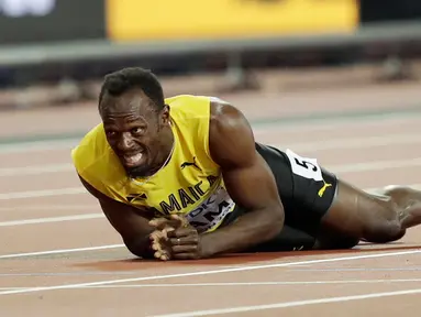 Pelari asal Jamaika, Usain Bolt terkapar di lintasan setelah terjatuh dan cedera di final 4x100 meter pada Kejuaraan Dunia Atletik di London, Sabtu (12/8). Bolt sempat tertatih-tatih sebelum akhirnya jatuh dan gagal melanjutkan lomba. (AP/Tim Ireland)