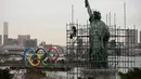 Pekerja memasang perancah pada replika Patung Liberty saat kapal tongkang membawa Cincin Olimpiade di Distrik Odaiba, Tokyo, Jepang, Jumat (17/1/2020). Cincin Olimpiade dengan tinggi 15,3 meter dan panjang 32,6 meter tersebut akan berada di sana hingga Olimpiade 2020 berakhir. (AP Photo/Jae C. Hong)