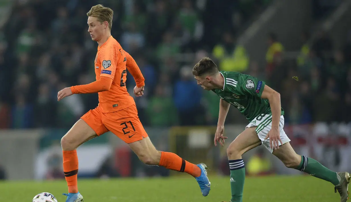 Gelandang Belanda, Frankie De Jong, menghindari kejara gelandang Irlandia Utara, Gavin Whyte, pada laga Kualifikasi Piala Eropa 2020 di Windsor Park, Belfast, Sabtu (16/11). Kedua negara bermain imbang 0-0. (AFP/Mark Marlow)