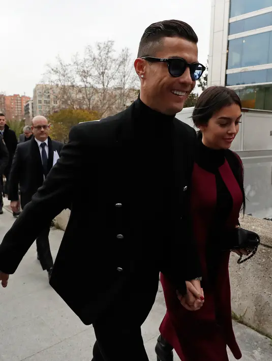 Pemain Juventus Cristiano Ronaldo menggandeng kekasihnya Georgina Rodriguez tiba di pengadilan di Kota Madrid, Selasa (22/1). Berdasarkan keterangan pengadilan, Ronaldo telah membayar sekitar 5,7 juta Euro agar tidak masuk bui. (AP Photo/Manu Fernandez)
