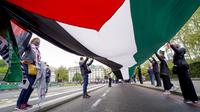 Orang-orang memegang bendera Palestina saat mereka berbaris dalam solidaritas untuk rakyat Palestina di tengah konflik yang sedang berlangsung dengan Israel selama demonstrasi di London, Inggris, Sabtu (15/5/2021). (AP Photo/Alberto Pezzali)