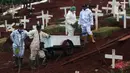 Petugas menunggu waktu pemakaman jenazah yang akan dimakamkan dengan protokol COVID-19 di TPU Pondok Ranggon, Jakarta, Sabtu (17/10/2020). Petugas terpaksa menggunakan gerobak dikarenakan kondisi tanah yang lengket dan licin akibat diguyur hujan. (Liputan6.com/Helmi Fithriansyah)