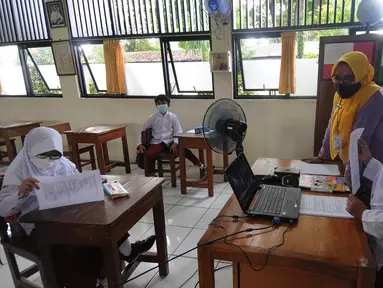 Murid kelas IV menunjukkan hasil tesnya kepada teman-temannya yang belajar online di rumah saat kegiatan belajar tatap muka di SDN Pondok Labu 14 Pagi di Cilandak, Jakarta Selatan, Jumat (4/6/2021). (merdeka.com/Arie Basuki)