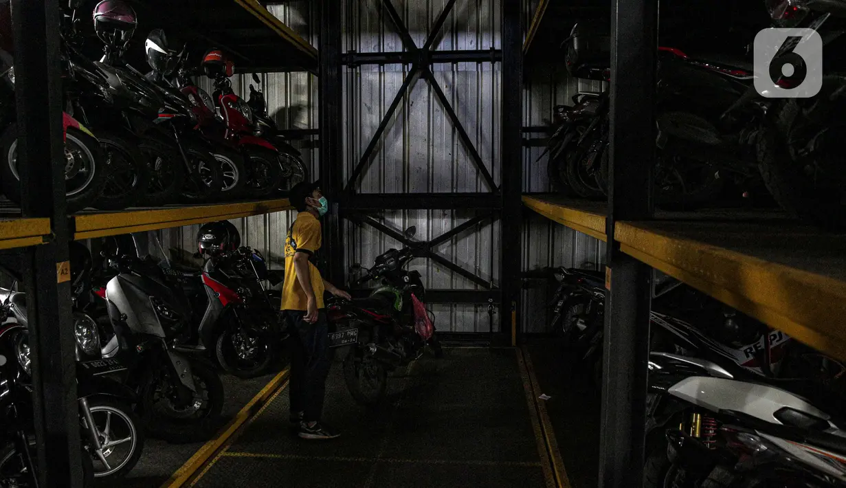 Pekerja menurunkan sepeda motor di Soul Parking, Kebon Kacang, Jakarta, Jumat (21/1/2022). Tempat parkir vertikal tersebut menerapkan sistem teknologi Compact Motor Storage atau sistem rak bersusun dengan lift barang. (Liputan6.com/Faizal Fanani)