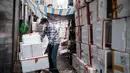 Seorang pekerja memakai masker sebagai tindakan pencegahan terhadap virus corona COVID-19 menumpuk kotak polystyrene di dekat toko yang menjual buah-buahan dan sayuran di Hong Kong (21/4/2020).  (AFP/Anthony Wallace)