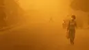 Seorang wanita berjalan sambil mengenakan masker di tengah badai pasir yang melanda Provinsi Homs, Senin  (7/8/2015).  Badai pasir ini juga melanda hampir seluruh kota di Suriah.  (REUTERS/Omar Sanadiki)