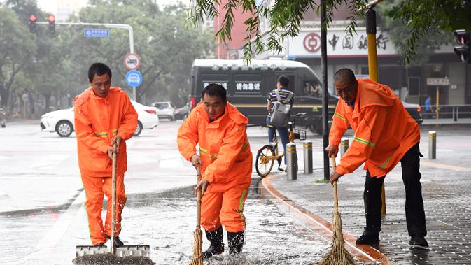 Orang-orang membersihkan genangan air di sebuah jalan di Distrik Haidian, Beijing, ibu kota China (12/8/2020). Badan meteorologi Beijing memperkirakan hujan deras akan mengguyur wilayah Beijing-Tianjin-Hebei antara Rabu (12/8) hingga Kamis (13/8). (Xinhua/Ren Chao)