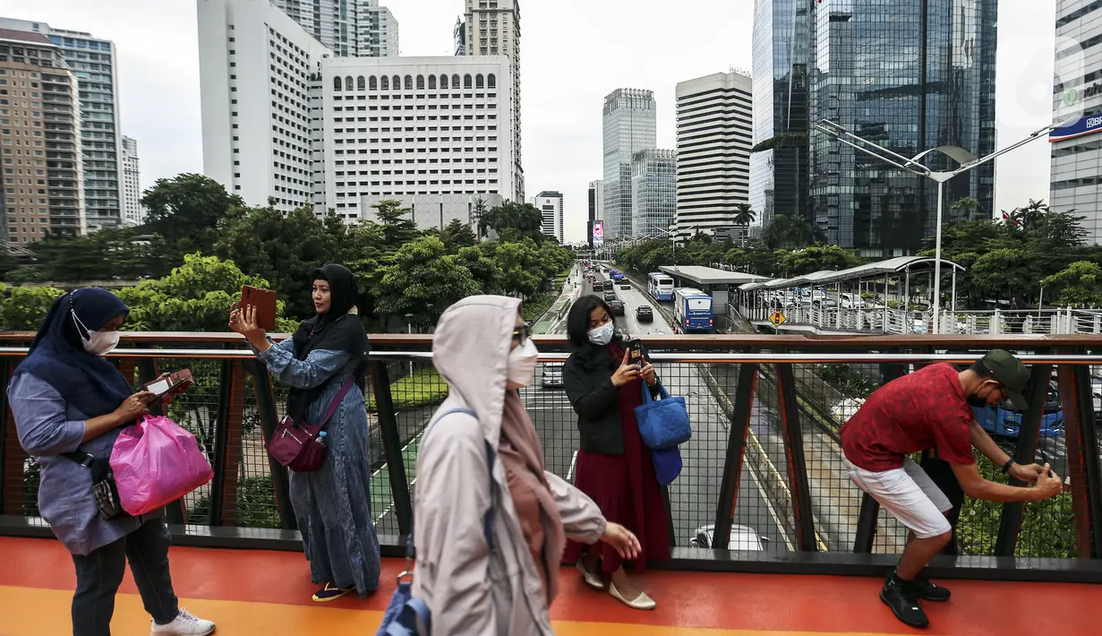 Warga berswafoto dengan kamera ponsel di Jembatan Penyeberangan Orang (JPO) Pinisi, Jalan Jenderal Sudirman, Karet, Jakarta, Selasa (15/3/2022). Belum lama ini, Pemprov DKI Jakarta meresmikan JPO berbentuk spesial tersebut yang membentang di atas Jalan Jenderal Sudirman. (Liputan6.com/Johan Tallo)