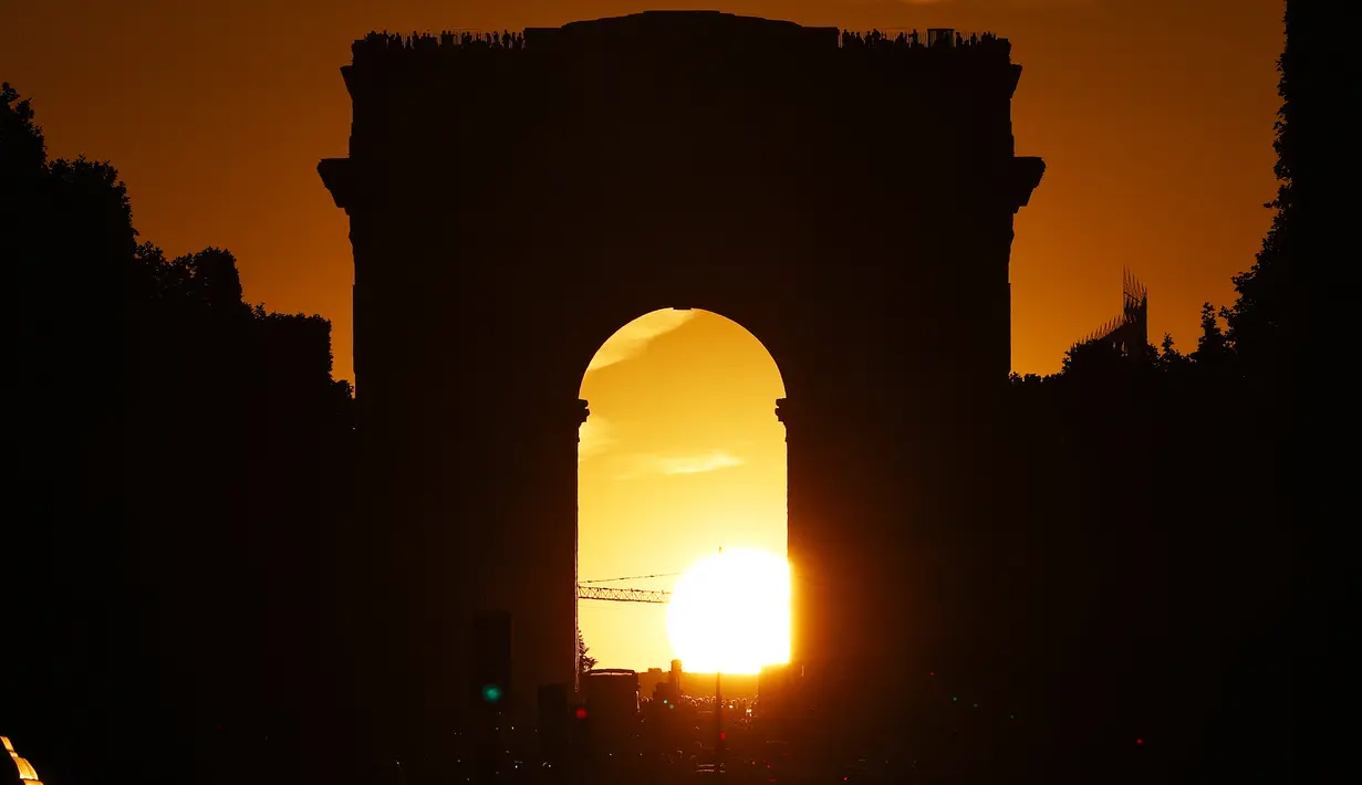 Foto yang diambil pada 2 Agustus 2022 menunjukkan Arc de Triomphe saat matahari terbenam, di Paris. Peristiwa yang dikenal sebagai "Paris Henge" ini di mana matahari sejajar dengan Champs Elysées, Arc de Triomphe dan Arche de la Défense. (Photo by Stefano RELLANDINI / AFP)