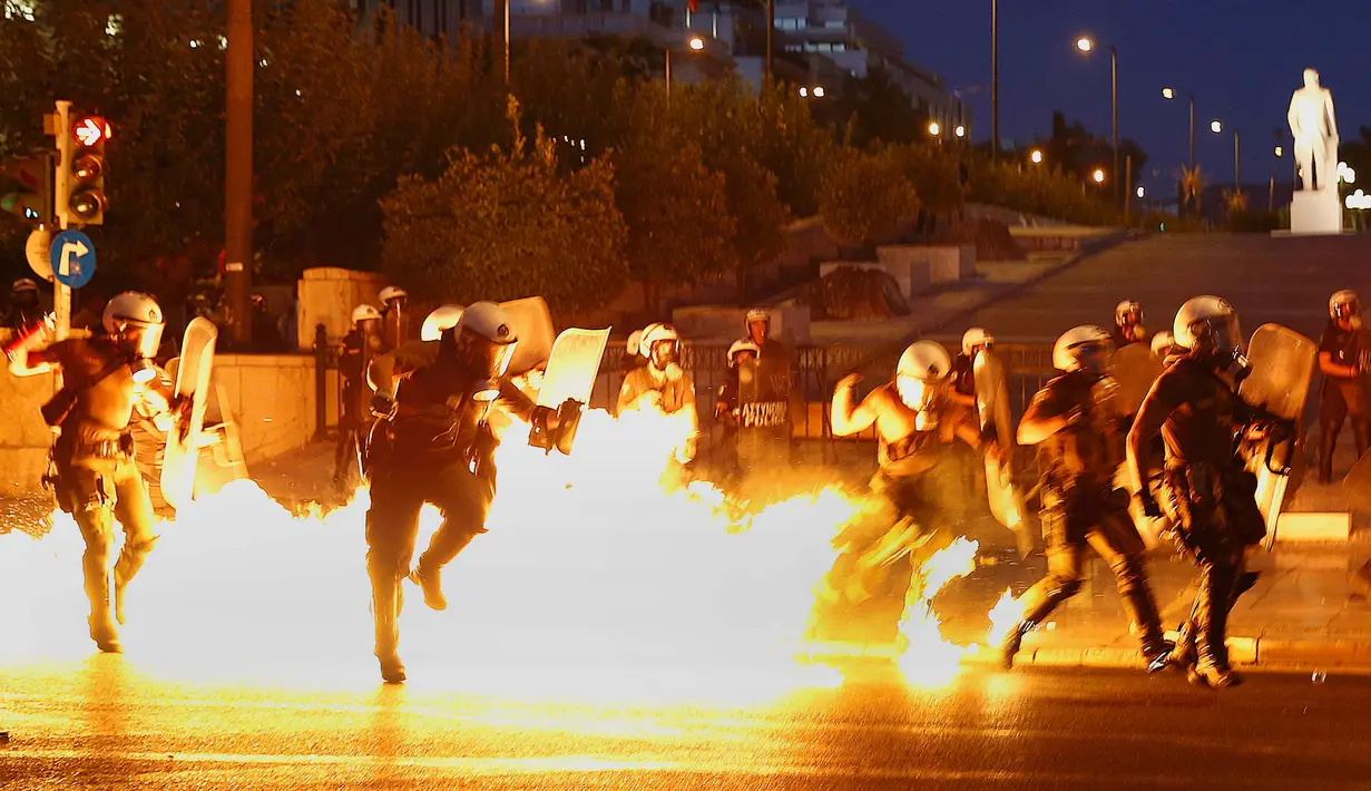 Polisi mencoba menghindari api bom molotov saat unjuk rasa anti-bailot di Athena, Yunani, Rabu (15/7/2015). Demonstran memblokir jalan bentuk penentangan kesepakatan bailout yang diklaim demi menyelamatkan Yunani. (REUTERS/Yannis Behrakis)