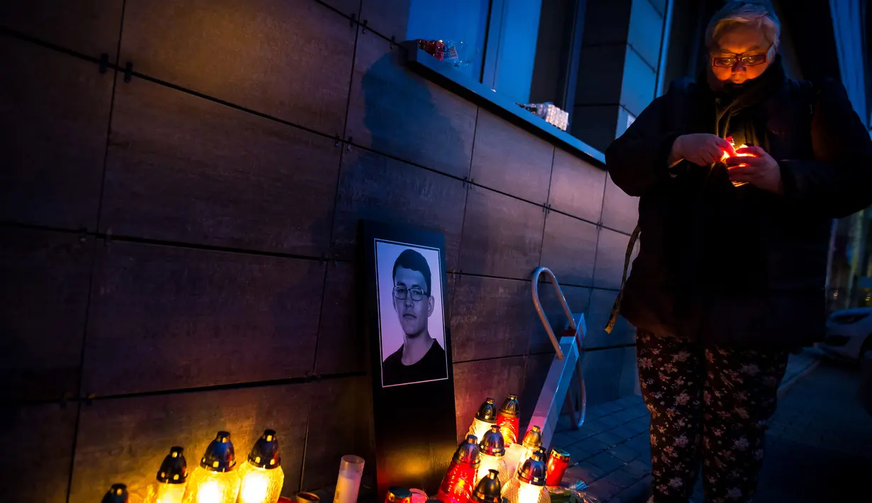 Seorang wanita menyalakan lilin di dekat foto Jan Kuciak di Bratislava (26/2). Pembunuhan itu terjadi di tengah pembuatan laporan investigatif Kuciak soal kasus dugaan kecurangan pajak yang melibatkan pengusaha. (AFP Photo/Vladimir Simicek)