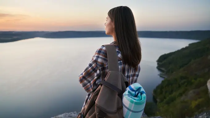 Seorang perempuan sedang menikmati sunset di tepi tebing (Foto Dok: Freepik/serhii_bobyk)