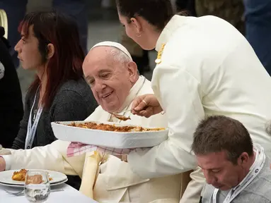 Paus Fransiskus duduk di sebuah meja dalam jamuan makan siang di Aula Paul VI, Vatikan, Minggu (17/11/2019). Paus Fransiskus mengundang sekitar 1.500 orang miskin, tunawisma, imigran dan pengangguran untuk makan siang dalam memperingati Hari Orang Miskin Sedunia. (AP/Alessandra Tarantino)