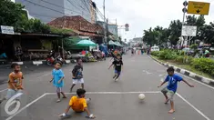Sejumlah anak bermain sepak bola di Jalan Tambak, Manggarai, Jakarta, Jumat (22/7). Minimnya lahan bermain, sejumlah anak manfaatkan jalanan untuk bermain. (Liputan6.com/Yoppy Renato)