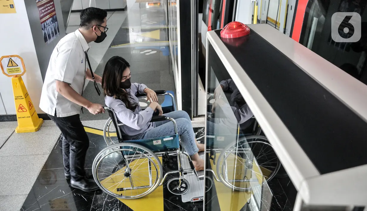 Petugas Light Rail Transit (LRT) Jakarta membantu penumpang disabilitas dengan kursi roda menaiki rangkaian gerbong kereta di Stasiun Pegangsaan Dua, Jakarta Utara, Selasa (24/1/2023). LRT Jakarta dilengkapi dengan berbagai fasilitas untuk para penumpang seperti Kesehatan dan Nursery room, Pos Sahabat Perempuan dan Anak (SAPA), bangku prioritas untuk penyandang disabilitas, orang tua, ibu hamil, dan anak-anak. (merdeka.com/Iqbal S. Nugroho)
