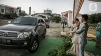 Pasangan mempelai bersama keluarga saat menyapa tamu undangan pada acara resepsi pernikahan secara "drive thru" di Bekasi, Jawa Barat, Sabtu (8/8/2020). Resepsi pernikahan secara drive thru menjadi alternatif pesta pernikahan guna mencegah penyebaran wabah COVID-19. (Liputan6.com/Faizal Fanani)