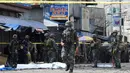 Polisi dan tentara berjaga pasca ledakan bom di Gereja Katolik Jolo, Filipina Selatan, Minggu (27/1). Bom kedua meledak di tempat parkir gereja ketika aparat setempat merespons. (Nickee Butlangan/AFP)