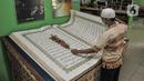 Petugas membersihkan Alquran raksasa koleksi Perpustakaan Jakarta Islamic Center (JIC), Jakarta Utara, Kamis (22/4/2021). Alquran raksasa tersebut merupakan pemberian dari Universitas Sains Alquran Wonosobo sebagai penghargaan atas berdirinya masjid JIC pada 2002. (merdeka.com/Iqbal S Nugroho)