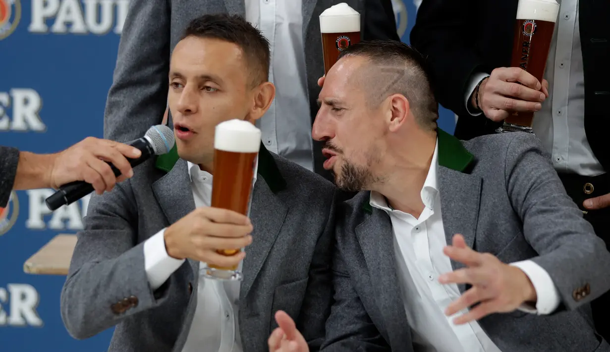 Pemain Bayern Munchen Rafinha (kiri) dan Franck Ribery mengenakan pakaian tradisional Bavaria bernyanyi untuk Thomas Mueller yang berulang tahun saat melakukan pemotretan sebuah perusahaan bir di Munich, Jerman, (13/9). (AP Photo / Matthias Schrader)