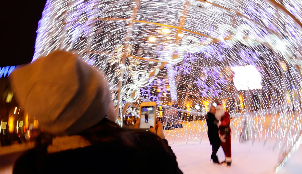 Pengunjung berfoto dekat bola natal raksasa di Octyabrskaya Square dan dekorasi untuk menyambut perayaan Natal 2018 dan Tahun Baru 2019 di Minsk, Belarus, Selasa (18/12). (AP Photo/Sergei Grits)