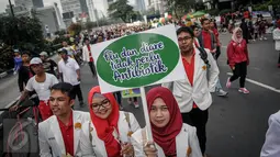 Peserta dari ISMAFARSI memperlihatkan poster saat melakukan longmarch memperingati Hari Apoteker Sedunia di kawasan Car Free Day, Jakarta, Minggu (25/9). Mereka mengajak masyarakat cerdas menggunakan obat, termasuk DaGuSiBu. (Liputan6.com/Faizal Fanani)