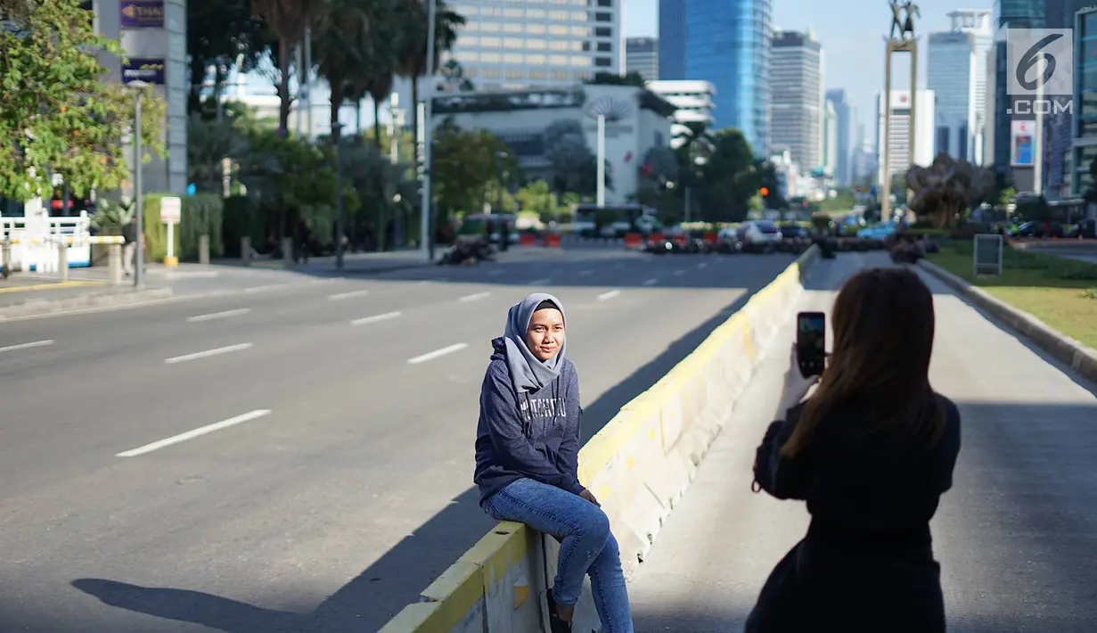 Seorang wanita berfoto dengan latar belakang Jalan MH Thamrin yang masih ditutup oleh aparat keamanan di Jakarta, Jumat (24/5/2019). Ditutupnya Jalan MH Thamrin terkait unjuk rasa menolak hasil Pemilu 2019 dimanfaatkan sebagian warga untuk berfoto. (Liputan6.com/Immanuel Antonius)
