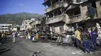 Petugas pemadam kebakaran berdiri dekat bangkai truk pengangkut BBM yang terbalik dan meledak di Cap-Haitien, Haiti, 14 Desember 2021. Ledakan tersebut menghanguskan mobil dan rumah serta menewaskan puluhan orang. (AP Photo/Joseph Odelyn)