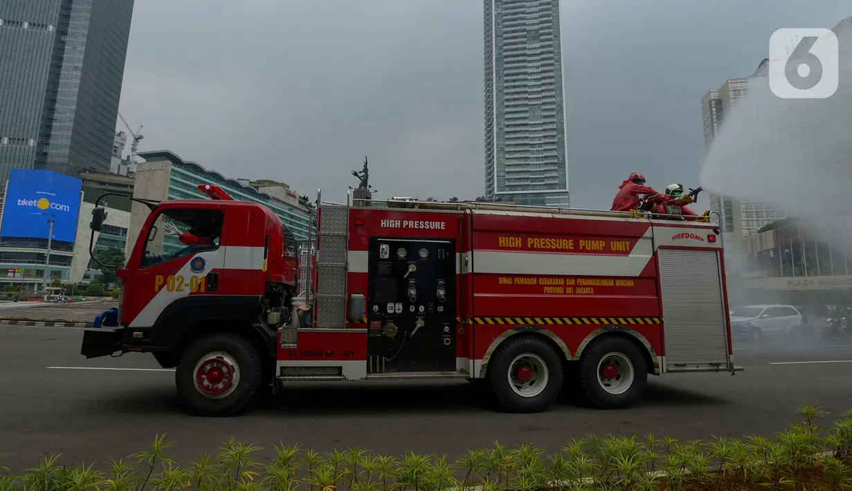 Petugas pemadam kebakaran (Damkar) melakukan penyemprotan cairan disinfektan di sepanjang jalan Thamrin-Sudirman, Jakarta, Sabtu (28/3/2020). Penyemprotan menggunakan mobil pemadam kebakaran tersebut bertujuan untuk mengantisipasi penyebaran Virus Corona (COVID-19). (merdeka.com/Imam Buhori)