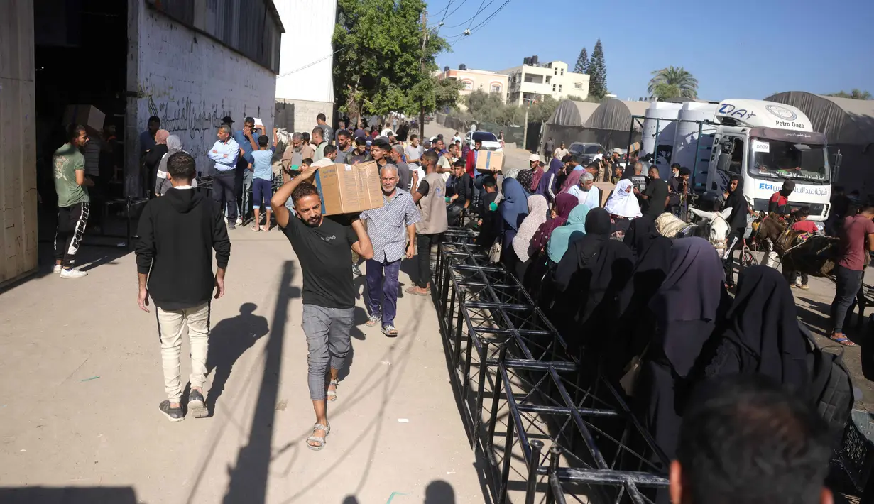 Sebagian besar perempuan (kanaa) mengantre untuk mengambil kotak makanan yang disediakan oleh Program Pangan Dunia (WFP) di pusat distribusi di desa Al-Zawayda, di tengah-tengah Jalur Gaza pada 27 Oktober 2025. (BASHAR TALEB/AFP)