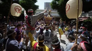 Peserta mengenakan pakaian tradisional Happi saat mengayunkan Mikoshi atau tempat suci portabel selama festival Tenno-sai di Kuil Susanoo di Tokyo, Jepang (3/6). Festival Tenno-sai ini digelar setiap tahunnya di Jepang. (AP Photo / Eugene Hoshiko)