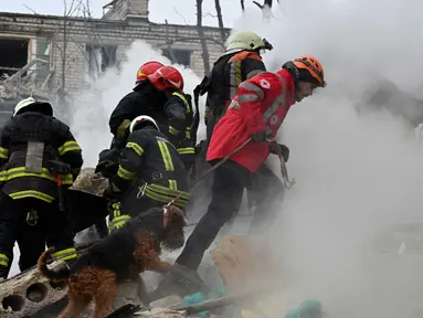 Anggota tim pencarian dan penyelamatan bekerja dengan anjing pelacak di lokasi serangan rudal di Kharkiv pada 23 Januari 2024. (SERGEY BOBOK/AFP)