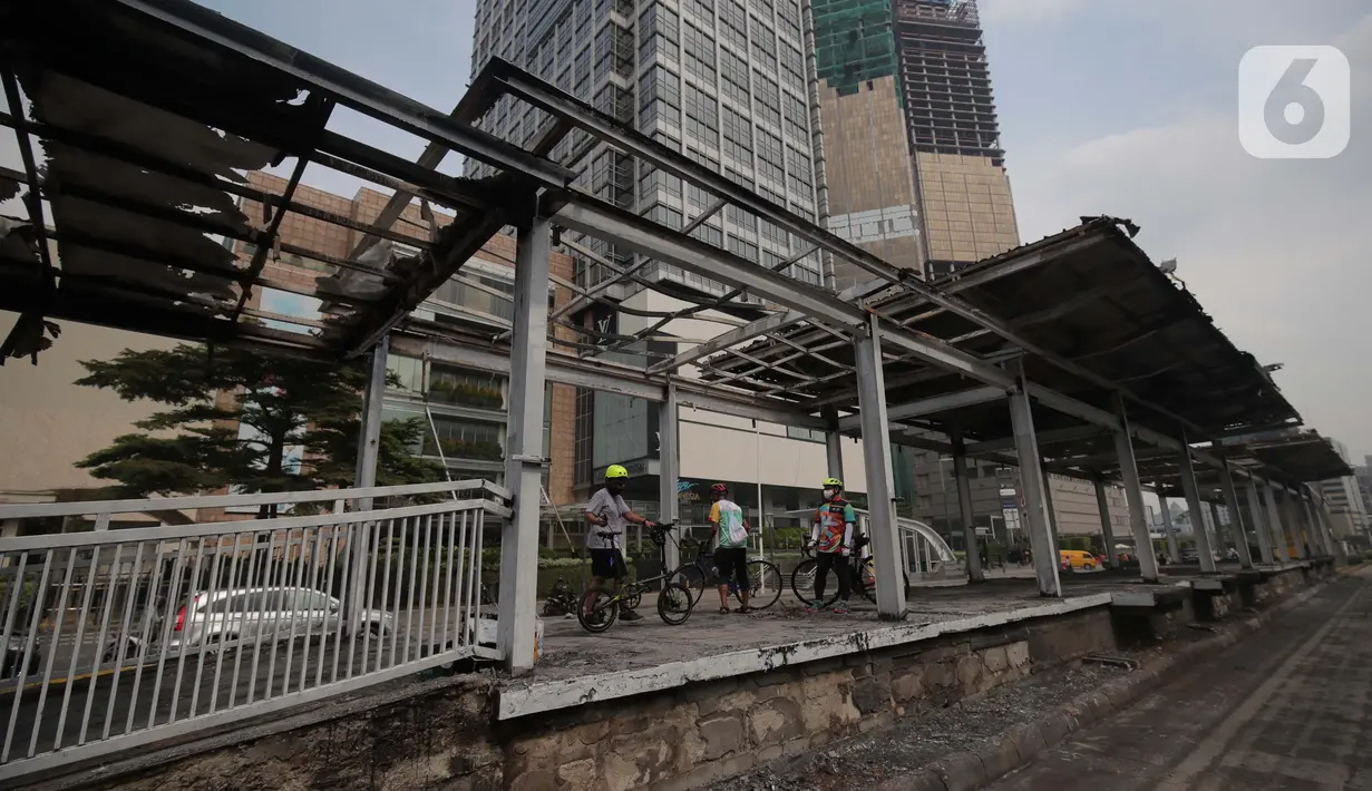 Sejumlah pesepeda melihat kerusakan Halte TransJakarta Bundaran HI, Jakarta, Jumat (9/10/2020). Demo menolak omnibus law Undang-Undang (UU) Cipta Kerja diwarnai kericuhan dan pembakaran terhadap sejumlah halte Transjakarta. (Liputan6.com/Angga Yuniar)