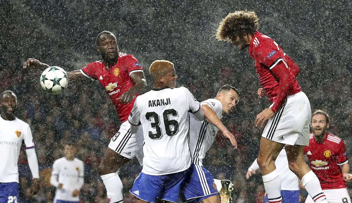 Sundulan pemain Manchester United, Marouane Fellaini (kanan) menembus pertahanan pemain Basel pada laga grup A Liga Champions di Old Trafford, Manchester, (12/9/2017). MU menang 3-0. (Martin Rickett/PA via AP)