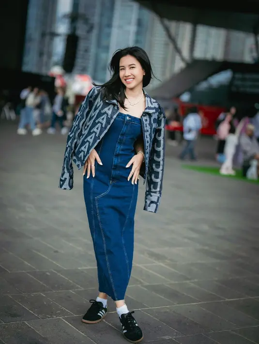 Shenina Cinnamon tampil mengenakan denim on denim di Busan. Strapless denim dress ditumpuknya mengenakan jaket denim bermotif logo tulisan brand. Ia padukan penampilannya dengan sneakers hitam. [Foto: Instagram/shenacinnamon]