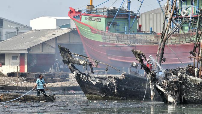 Sejumlah pria melakukan pendinginan kapal yang ludes dilalap api di Pelabuhan Muara Baru, Jakarta, Minggu (24/2). Sebanyak 23 unit kendaraan pemadam dikerahkan untuk memadamkan api saat kebakaran. (Merdeka.com/Iqbal Nugroho)