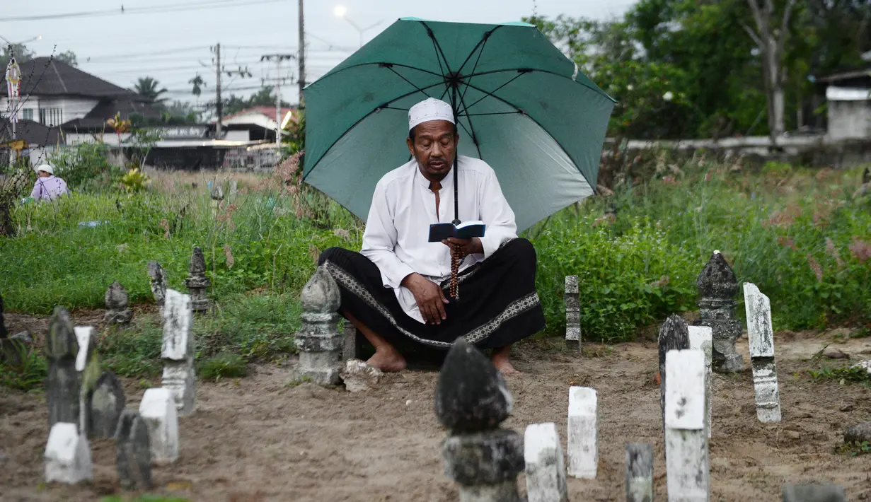 Seorang pria memanjatkan doa di makam kerabatnya saat Idul Fitri di Provinsi Narathiwat, Thailand, Rabu (5/6/2019). Tradisi ziarah kubur saat Idul Fitri ini mirip dengan apa yang biasa dilakukan muslim di Indonesia. (MADAREE TOHLALA/AFP)