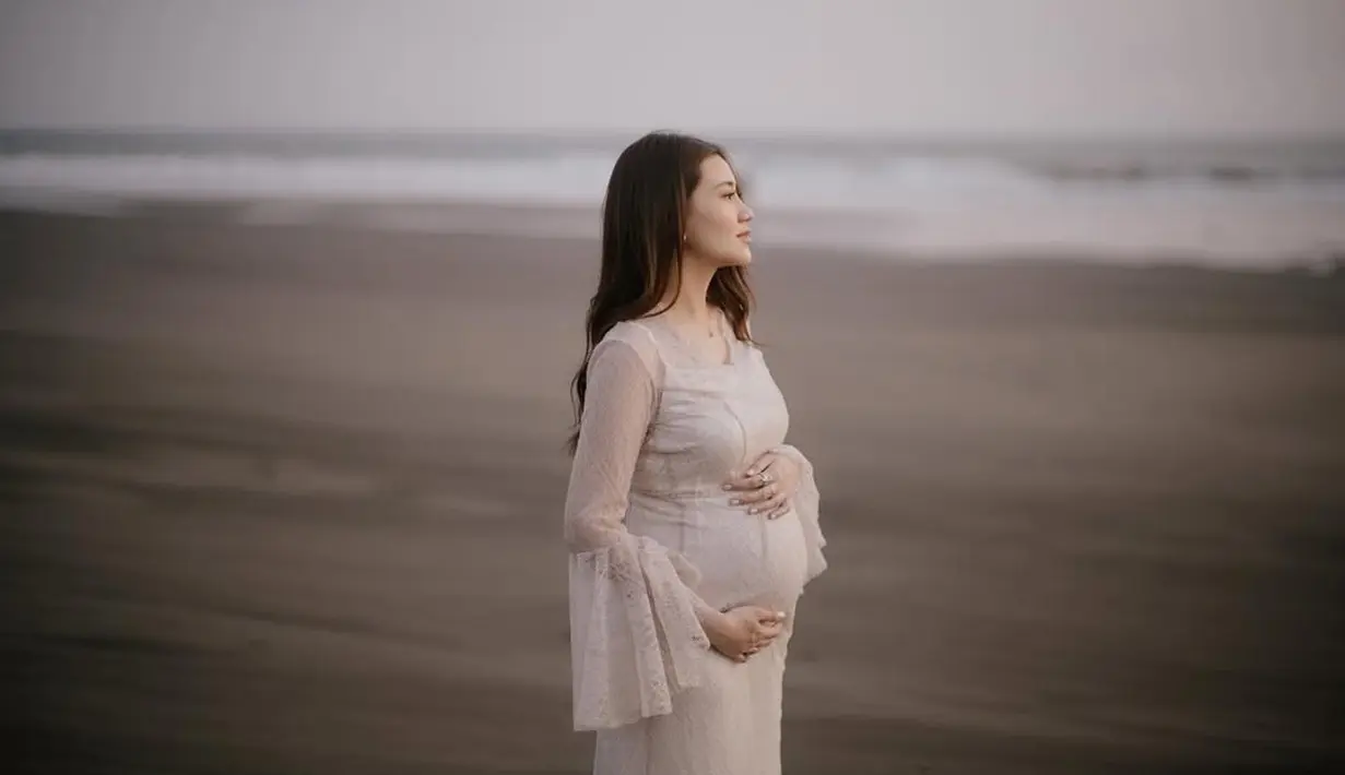 Dalam balutan dress putih berbahan lace transparan dari @jessiegunawanstudio, ia memperlihatkan baby bump-nya dengan penuh kebanggaan dan kebahagiaan. Siluet dress yang membalut tubuhnya menonjolkan keanggunan Aaliyah sekaligus memberikan kesan dreamy yang begitu kental.  [@aaliyah.massaid].
