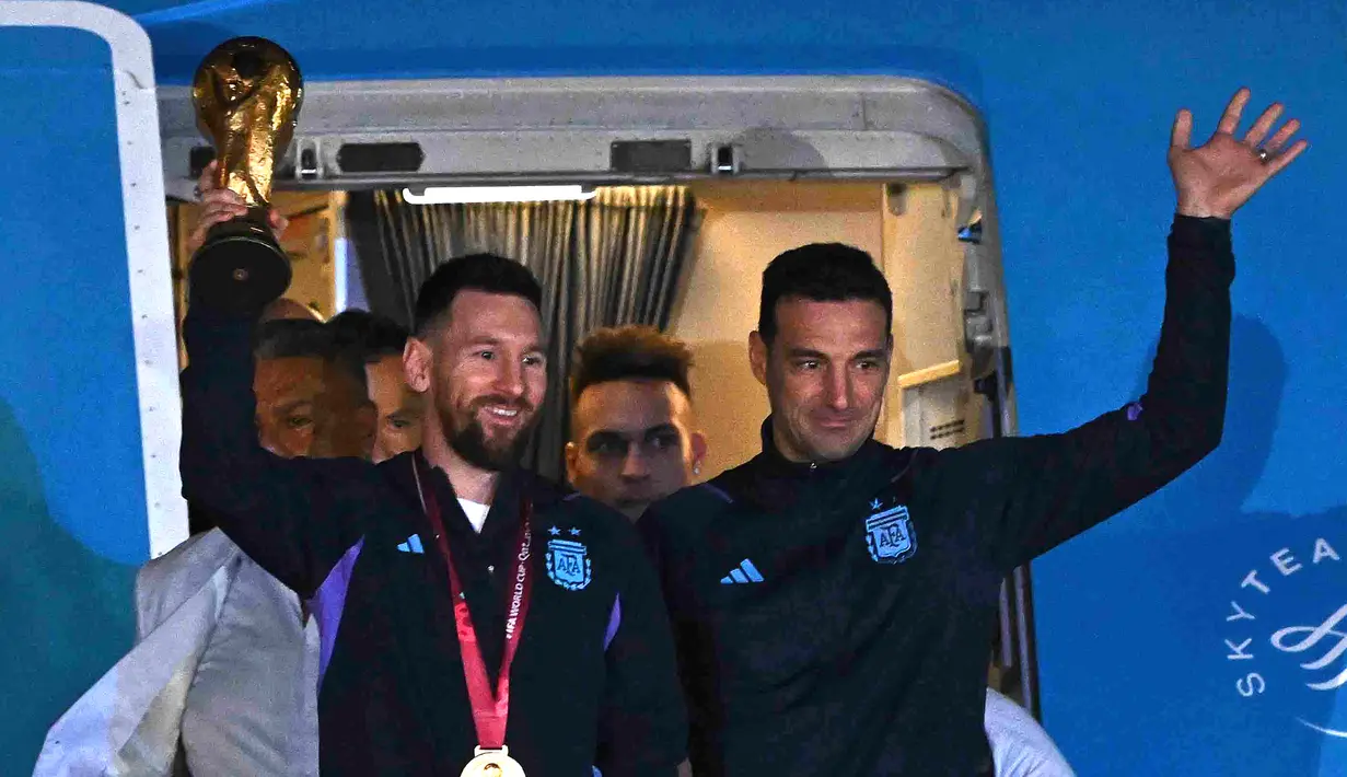 Kapten Argentina Lionel Messi (kiri) memegang Trofi Piala Dunia 2022 bersama pelatih Lionel Scaloni saat turun dari pesawat setibanya di Bandara Internasional di Ezeiza, provinsi Buenos Aires, Argentina (20/12/2022). Argentina tampil sebagai juara Piala Dunia 2022 setelah menumpas Prancis melalui adu penalti di final. (AFP/Luis Robayo)
