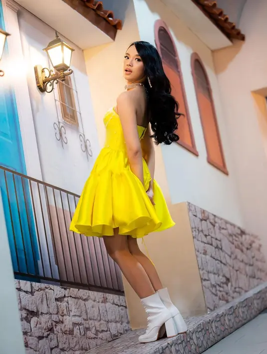 Atau strapless dress berwarna kuning polos, yang dipadunya dengan midi boots putih, Lyodra berhasil menghadirkan tampilan anggun, yang playful. Foto: Instagram.