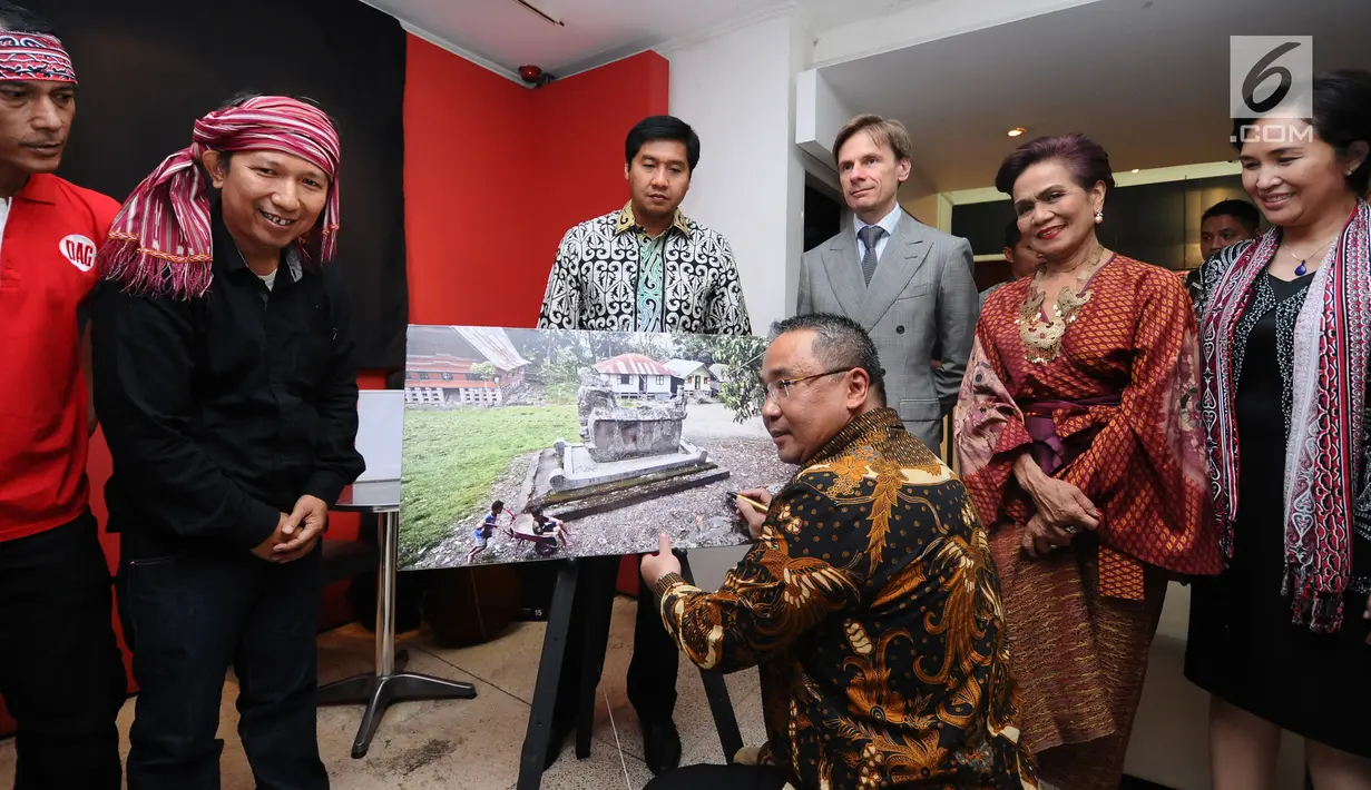 Menteri Desa, PDT dan Transmigrasi, Eko Putro Sandjojo menandatangani foto saat membuka Peluncuran Buku Danau Toba dan Mangongkal Holi di Jakarta, Kamis (24/8). Acara juga dimeriahkan dengan pameran foto budaya Batak. (LIputan6.com/Helmi Fithriansyah) 