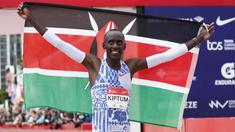Pelari Kenya, Kelvin Kiptum melakukan selebrasi dengan membentangkan bendera negaranya setelah memenangkan Chicago Marathon 2023 di Chicago, Illinois, Amerika Serikat, 8 Oktober 2023. Ia memecahkan rekor sebagai pelari marathon tercepat di dunia dengan mencatatkan waktu 2 jam 35 detik. (AFP/Kamil Krzaczynski)