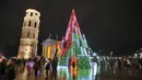 Pohon Natal yang menyala terlihat di dekat katedral di Vilnius, Lithuania pada 28 November 2020. Pohon natal raksasa yang dihiasi berbagai ornamen lampu hias tersebut membuat kawasan di ibu kota Lithuania menjadi terang. (PETRAS MALUKAS / AFP)